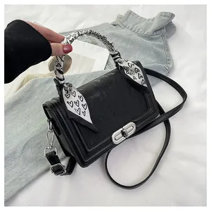 Detail of black embossed crossbody bag with heart pattern scarf and silver metal buckle