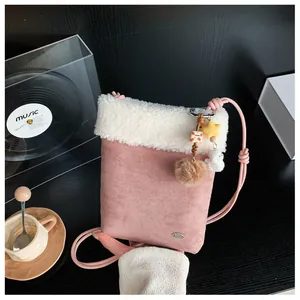 Détail du sac bandoulière en similicuir rose avec bordure en peluche et pendentif