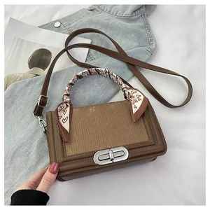 Detail of a brown leather crossbody bag with silver twist lock and decorative scarf handle