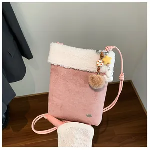 Détail du sac bandoulière rose en suédine avec bordure en fausse fourrure blanche et breloques