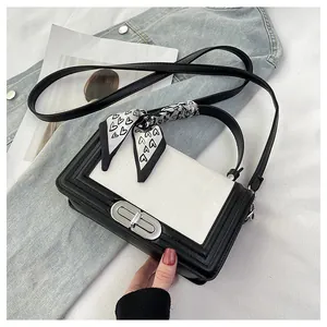 Close-up of minimalist black and white crossbody bag with heart print silk scarf detail