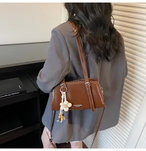 Side view of brown leather tote bag with white flower charm and wooden bead accessory