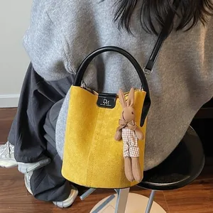 Minimalist yellow suede bucket bag with black leather handle and cute knit bunny charm