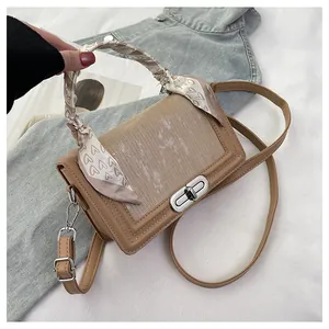 Detail of khaki leather handbag featuring silver rotary lock and stylish silk scarf wrap