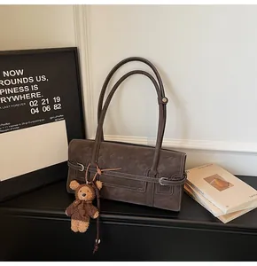Detail of vintage brown tote bag with contrast stitching and bear plush charm