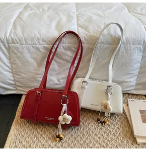 Detail of red and white patent leather tote bags with flower charms on a woven mat