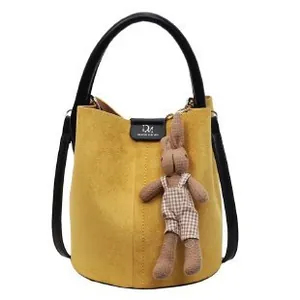 Yellow suede bucket bag with black leather straps and a cute rabbit charm pendant