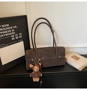 Detail of coffee suede tote bag featuring contrast stitching and cute teddy bear charm