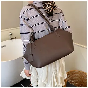 Détail d'un grand sac cabas en cuir marron foncé avec texture grainée sur un mannequin