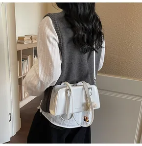 Detail of white glossy leather tote bag with wooden bead tassel and silver logo text