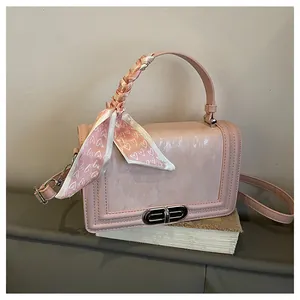 Close-up of pink crossbody bag with pearlescent texture and silk scarf handle detail