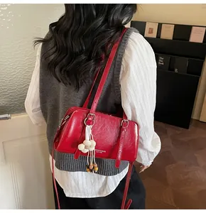 Detail of red glossy leather tote bag with floral tassel charm and decorative white text