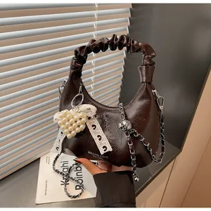 Detail of dark brown glossy patent leather handbag with pearl heart and lace bow accent