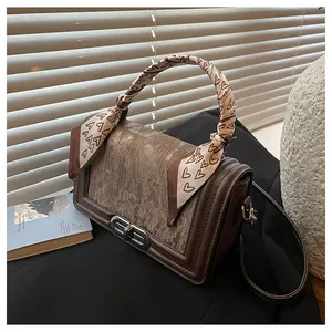 Detail of dark brown leather crossbody bag with heart print scarf wrapped handle