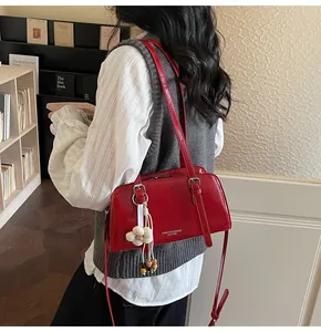 Detail of red patent leather shoulder bag with floral pendant in a cozy bookstore