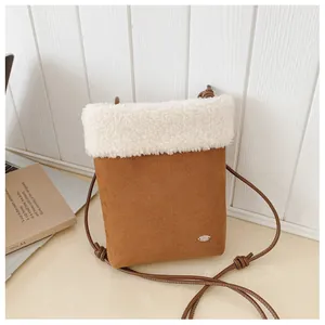 Gros plan sur le sac bandoulière en daim marron avec bordure en polaire blanche douce
