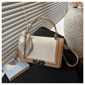 Detailed close-up of a two-tone crossbody bag with a decorative scarf on a leather handle