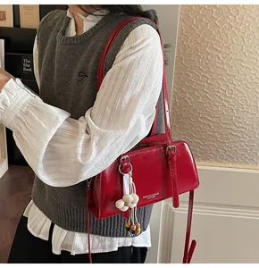 Detail of red glossy faux leather shoulder bag with floral charm and adjustable strap