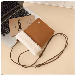 Détail du sac à bandoulière en daim marron avec bordure en polaire blanche et fine lanière