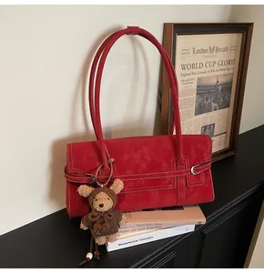 Detail of red vintage shoulder bag with white contrast stitching and cute plush bear charm