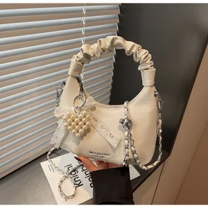 Detail showing creamy white pleated PU leather handbag with large heart pearl pendant and chain