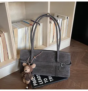 Detail of vintage suede shoulder bag with white contrast stitching and plush bear charm
