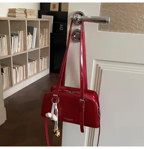 Detail of red patent leather tote bag hanging on a door handle with a floral charm