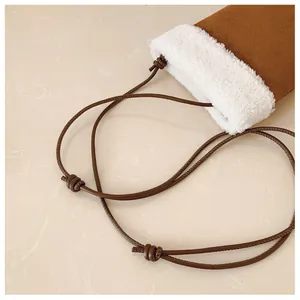 Vue détaillée du mini sac à bandoulière en daim marron avec bordure en fourrure et nœud