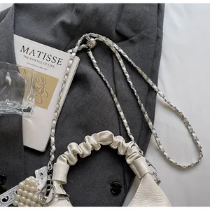 Detail of cream white pleated handle bag with pearl lace charm and silver chain strap