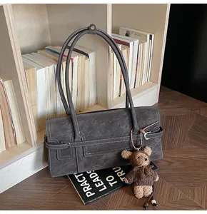 Detail of vintage tote bag with contrast stitching and plush bear charm on wood