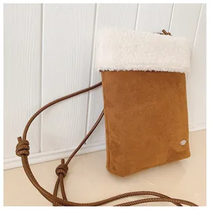 Détail du mini sac bandoulière en daim marron avec bordure en peluche blanche et logo