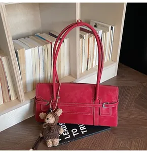 Detail of red vintage shoulder bag with white contrast stitching and a cute bear charm