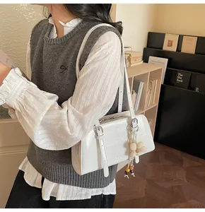 Detail of white leather tote bag featuring a floral charm and silver metal buckle