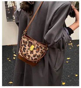 Detail van luipaardprint bucket bag met bruine leren bies en gouden metalen sluiting