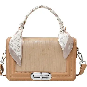 Khaki minimalist crossbody handbag with textured flap, metal buckle, and silk scarf wrap