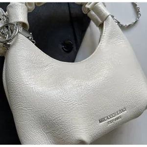 Close-up of pleated cream leather bag texture with embossed logo and silver chain detail