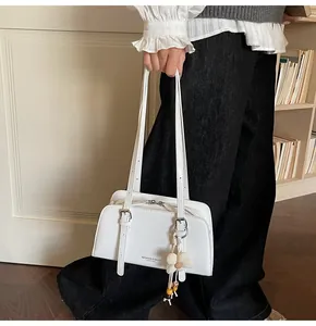 Close-up of white leather shoulder bag with flower charm and silver hardware detail