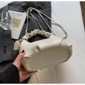 Detail of off-white bucket bag with ruched handle, chain strap and pearl heart charm