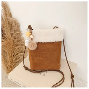 Détail du sac bandoulière d'hiver avec bord en peluche, charms et bandoulière en corde