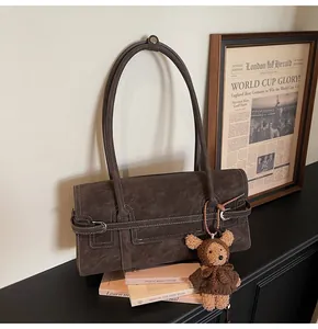 Detail of dark brown vintage shoulder bag with matte finish and cute teddy bear charm