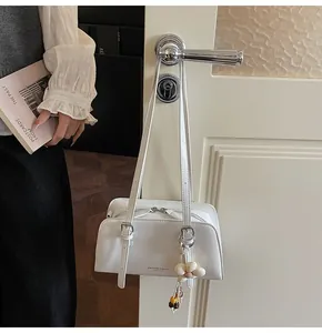 Detail of white leather tote bag with floral charm and adjustable shoulder straps