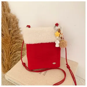 Détail du sac d'hiver avec bordure en sherpa blanc, daim rouge et breloque en peluche