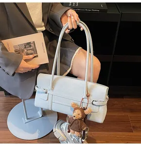 Detail of light blue rectangle shoulder bag with belt buckle and cute teddy bear charm