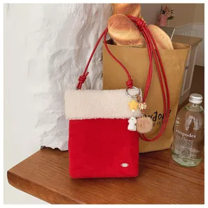 Vue détaillée du sac bandoulière en velours rouge avec fausse fourrure et breloques
