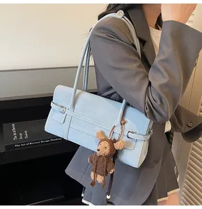 Light blue shoulder bag with bear plush charm shown on person for style and scale