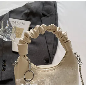 Detail of cream pleated handle and faux leather texture with pearl bow charm