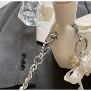 Detail of off-white lychee texture leather mini bag with silver chain and pearl charm