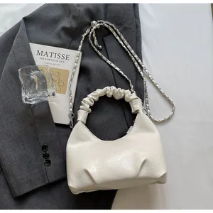Detail of off-white pleated handbag with cloud-shaped handle and silver metal chain strap