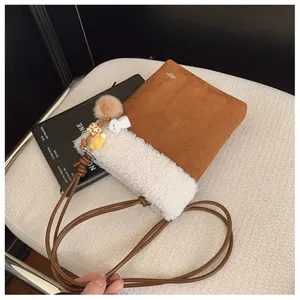 Détail du sac bandoulière hiver avec bordure peluche et breloques sur canapé doux