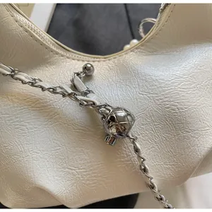 Macro detail of white pleated leather bag with silver chain and quilted metal ball
